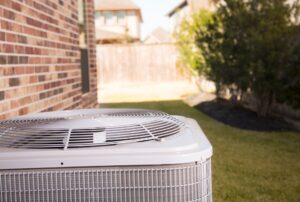 Outdoor view of an air conditioning unit next to a brick house in a suburban backyard, representing professional HVAC services offered by Family Heating and Cooling in Westport, Dartmouth, and surrounding Massachusetts areas. AC short cycling, AC short cycle Repair, AC Maintenance, AC Replacement, HVAC Services Westport, Air Conditioner Installation Dartmouth, Outdoor AC Unit Fall River, Energy-Efficient HVAC New Bedford, Residential Cooling Systems Fairhaven, Family Heating and Cooling Marion, HVAC Preventative Maintenance Massachusetts, Air Conditioning Unit, HVAC System, Outdoor AC, Brick House HVAC, Suburban Cooling, Family Heating and Cooling, Massachusetts HVAC Services, Energy-Efficient Cooling, AC Repair Services, AC Maintenance Tips, Residential HVAC Systems,